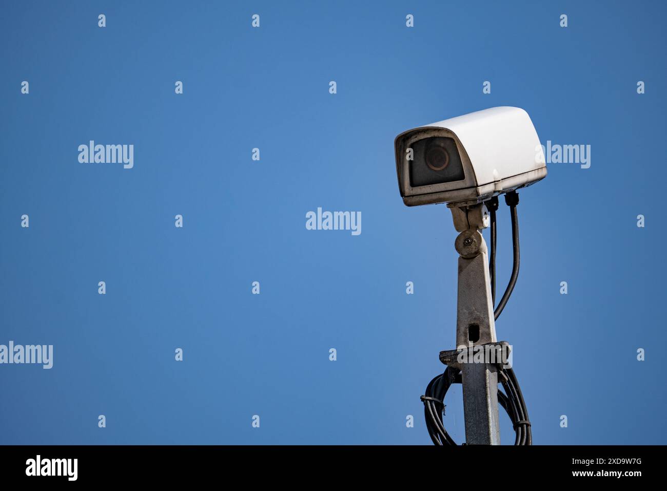 Telecamera di sicurezza bianca montata sul palo contro il cielo blu Foto Stock