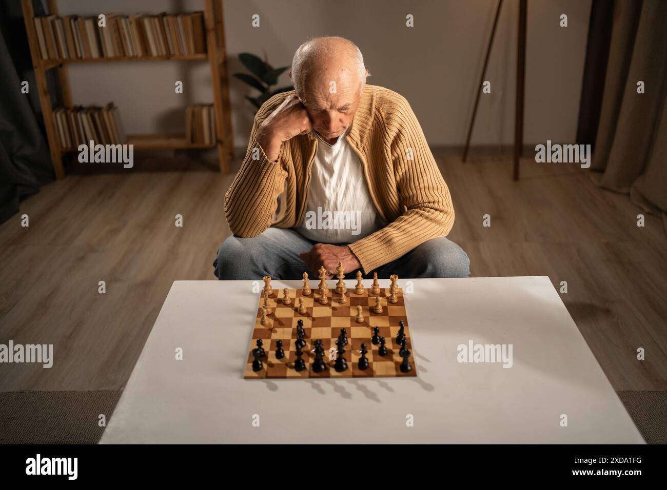Pensionati attivi. Uomo anziano che pensa mentre gioca a scacchi a casa. Foto Stock