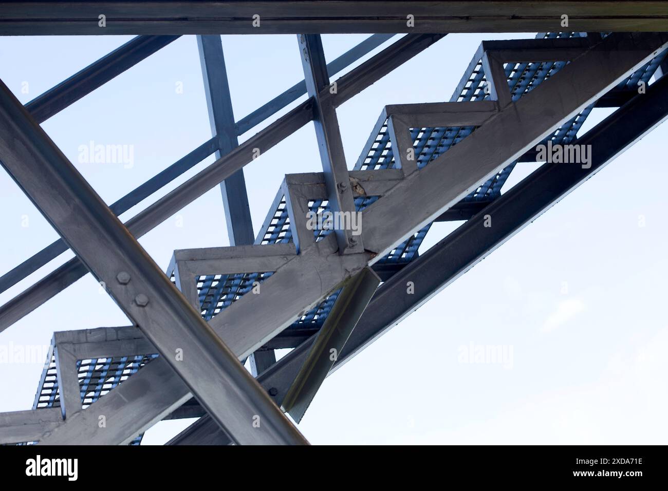 Scala in ferro per lavori di manutenzione. Struttura in acciaio e travi gli elementi strutturali contro il cielo blu dal punto di vista basso. Foto Stock