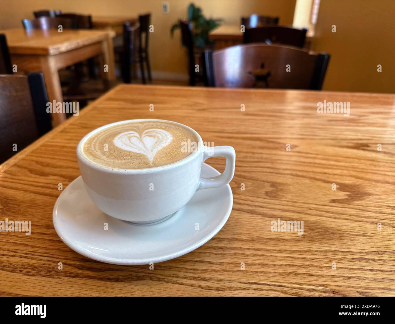 Tazza da caffè con latte art a forma di cuore su un tavolo in legno nella caffetteria Foto Stock