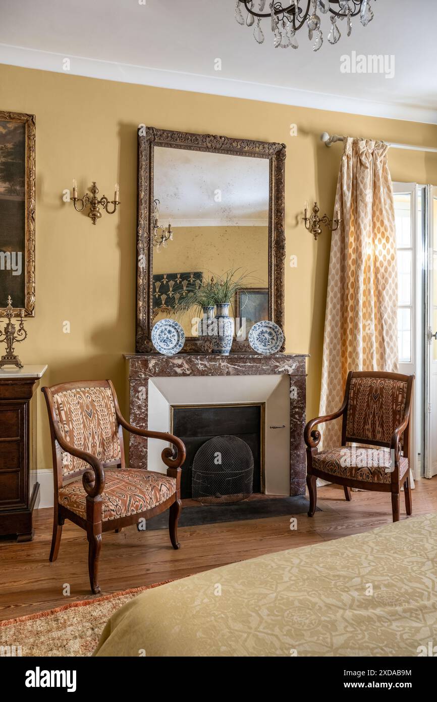 Un paio di poltrone imbottite sul caminetto nella camera da letto gialla in un hotel ristrutturato in pietra risalente al 1770 a Saulieu, Borgogna, Francia. Foto Stock