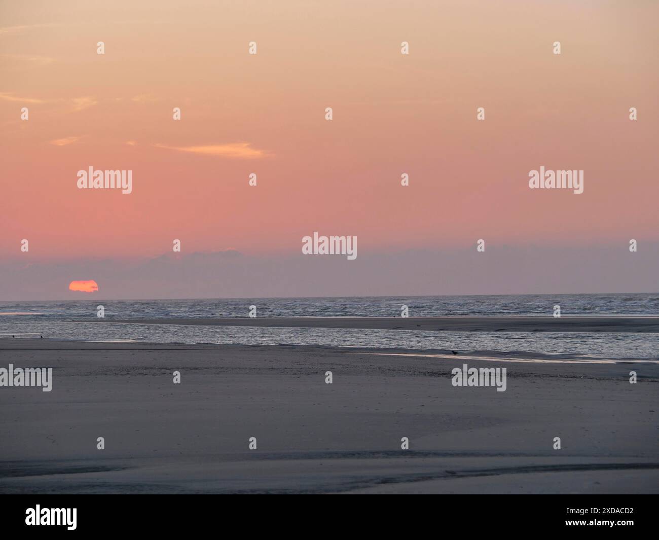 Il tramonto sul mare calmo crea un'atmosfera tranquilla e tranquilla, juist, frisia orientale, germania Foto Stock