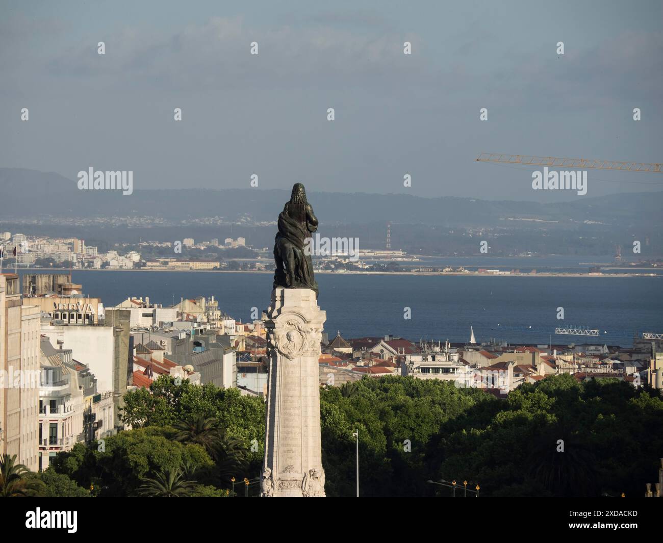 Una statua monumentale che si affaccia su un paesaggio urbano con vista mare e colline sullo sfondo, lisbona, portogallo Foto Stock