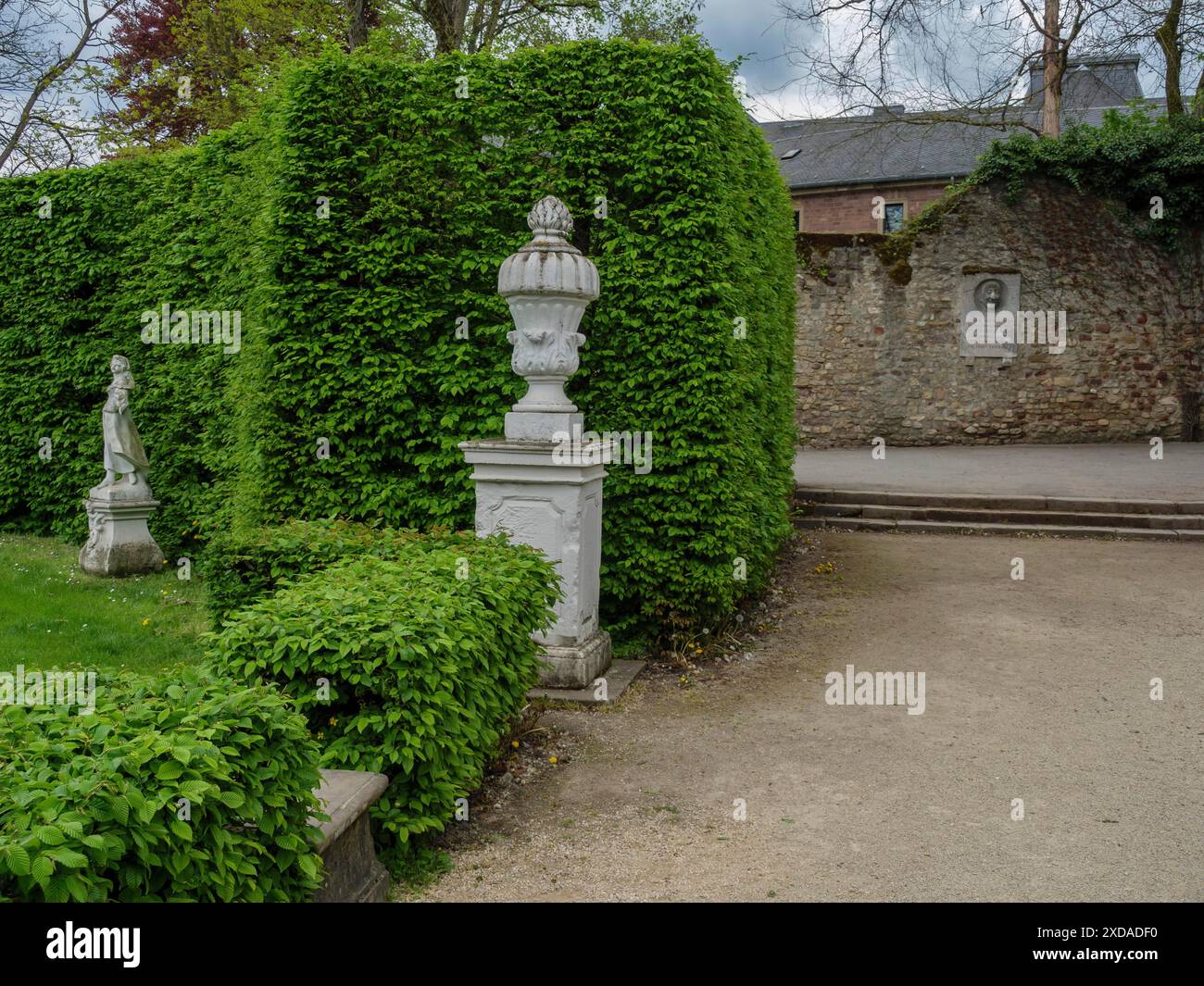 Giardino ben tenuto con siepi e statue, circondato da un vecchio muro, treviri, germania Foto Stock