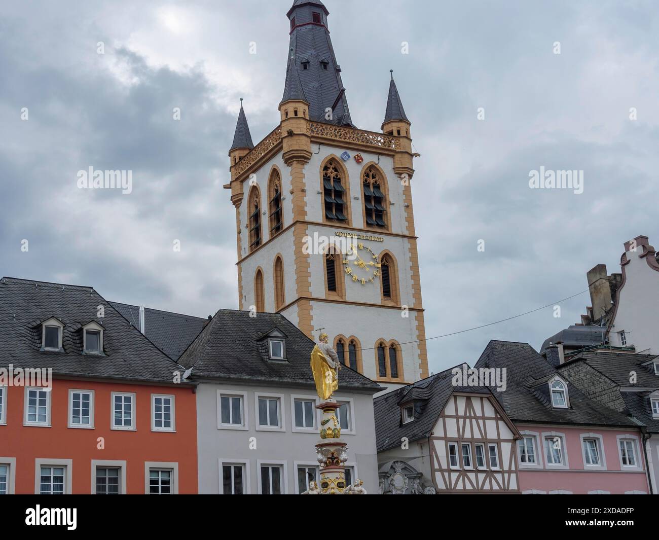 Piazza storica con architettura colorata e una torre con un orologio sotto un cielo nuvoloso, treviri, germania Foto Stock