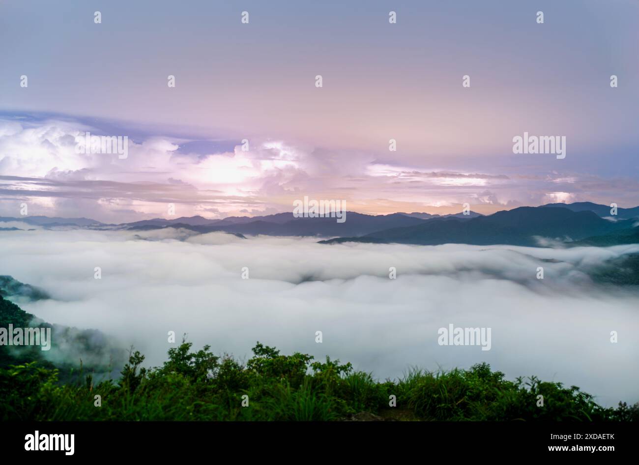 In una notte d'estate, il mare di nuvole ondeggia e lampeggia un lampo. Vista sulle montagne che circondano Emerald Reservoir. Distretto di Xindian, Taiwan. Foto Stock