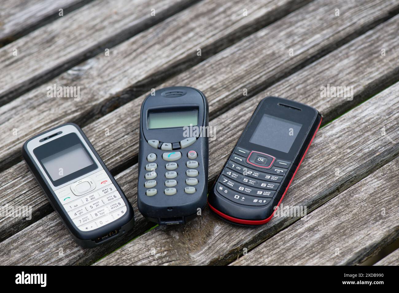 Vecchi telefoni cellulari su un vecchio tavolo di legno intemprato Foto Stock