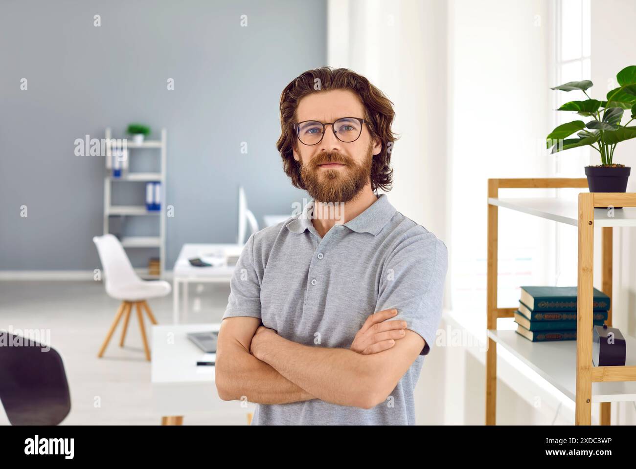 Ritratto di un dipendente intelligente e sicuro di sé che pone sullo sfondo di un ufficio moderno. Foto Stock
