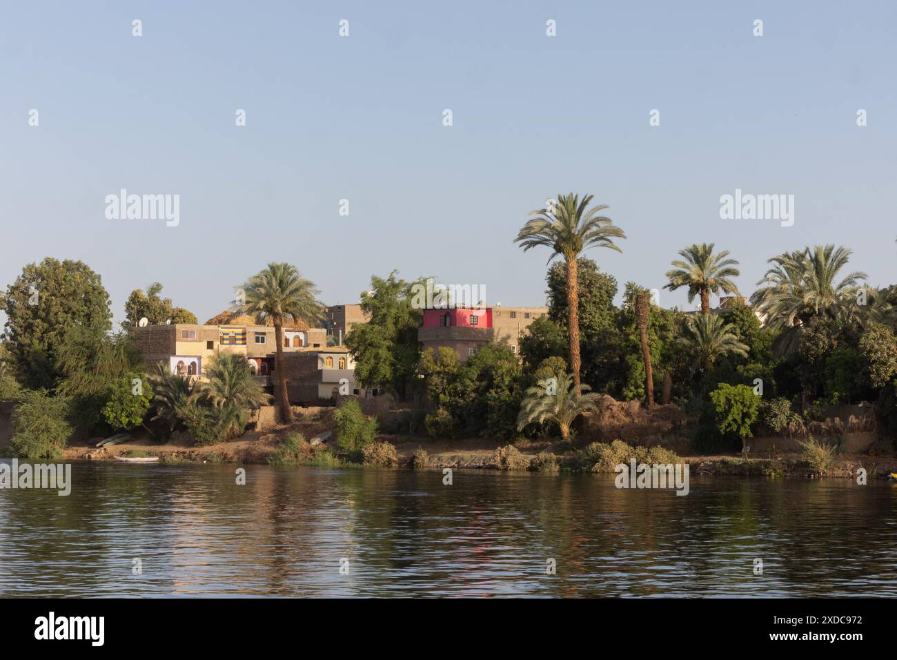 Case borghesi dai colori vivaci al sole della mattina presto lungo il fiume Nilo tra Esna e El-Kab, Egitto. Foto Stock