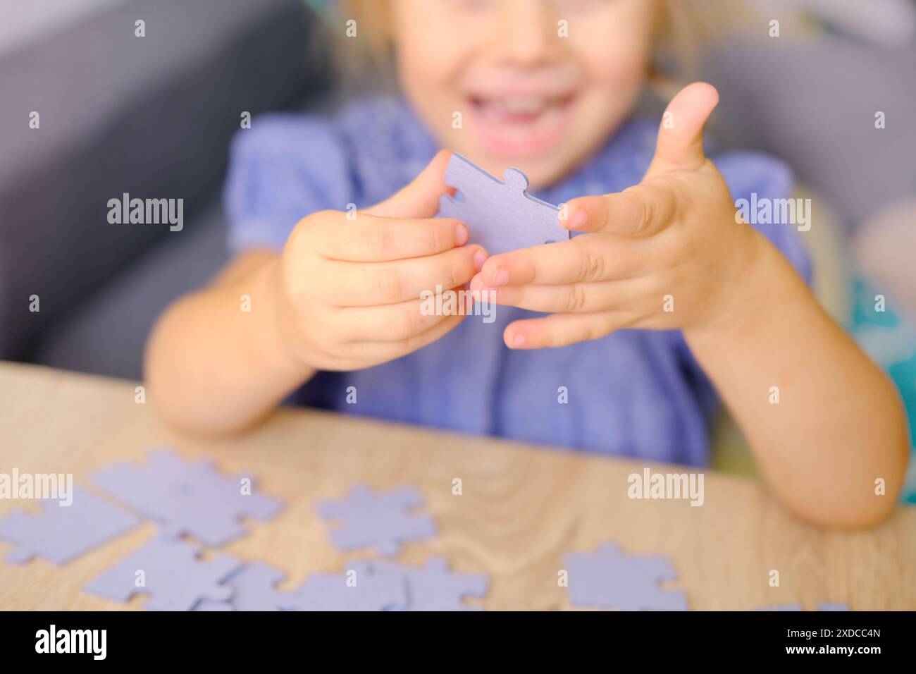 ragazza allegra e funky di 3 anni che assembla puzzle, forma pezzi di cartone, assembla puzzle, sviluppo cognitivo attraverso la risoluzione di puzzle Foto Stock