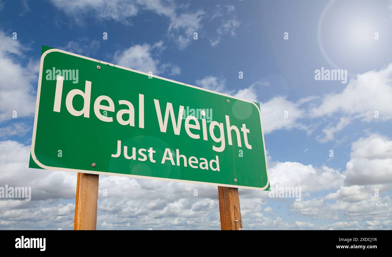 Ideal Weight poco più avanti, segnaletica stradale verde, nuvole e cielo blu. Foto Stock