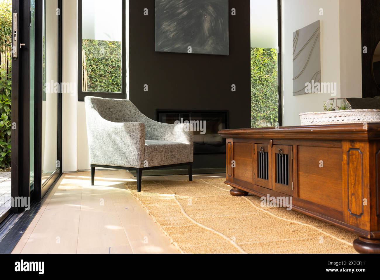 Luce del sole che scorre nel moderno soggiorno con poltrona e tavolino da caffè in legno, spazio fotocopie Foto Stock