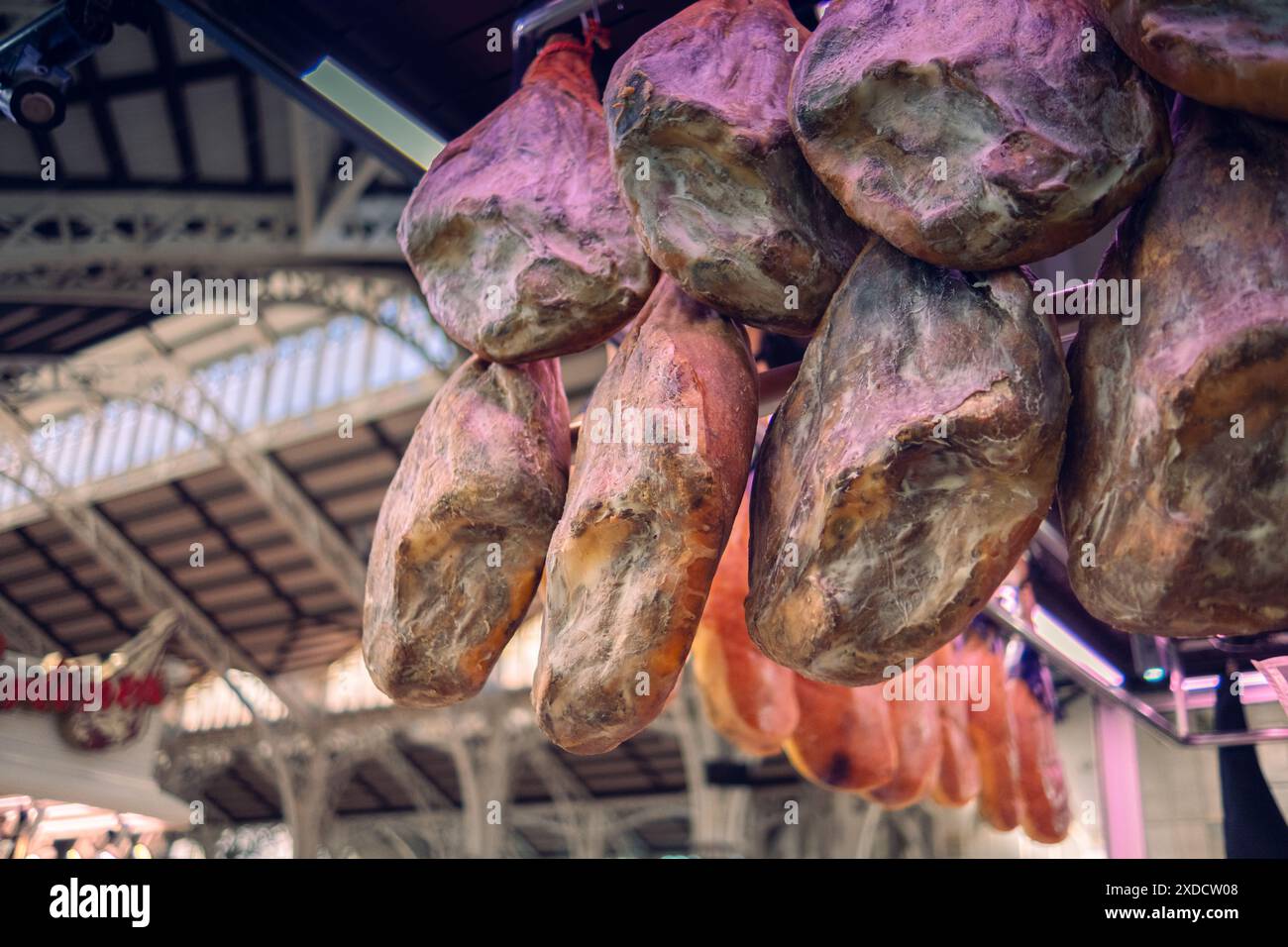 Vendere jamon sul mercato. Il prosciutto sotto forma di mozziconi di maiale è appeso al bancone, in attesa dei clienti. Prodotto nazionale della Spagna. Foto Stock