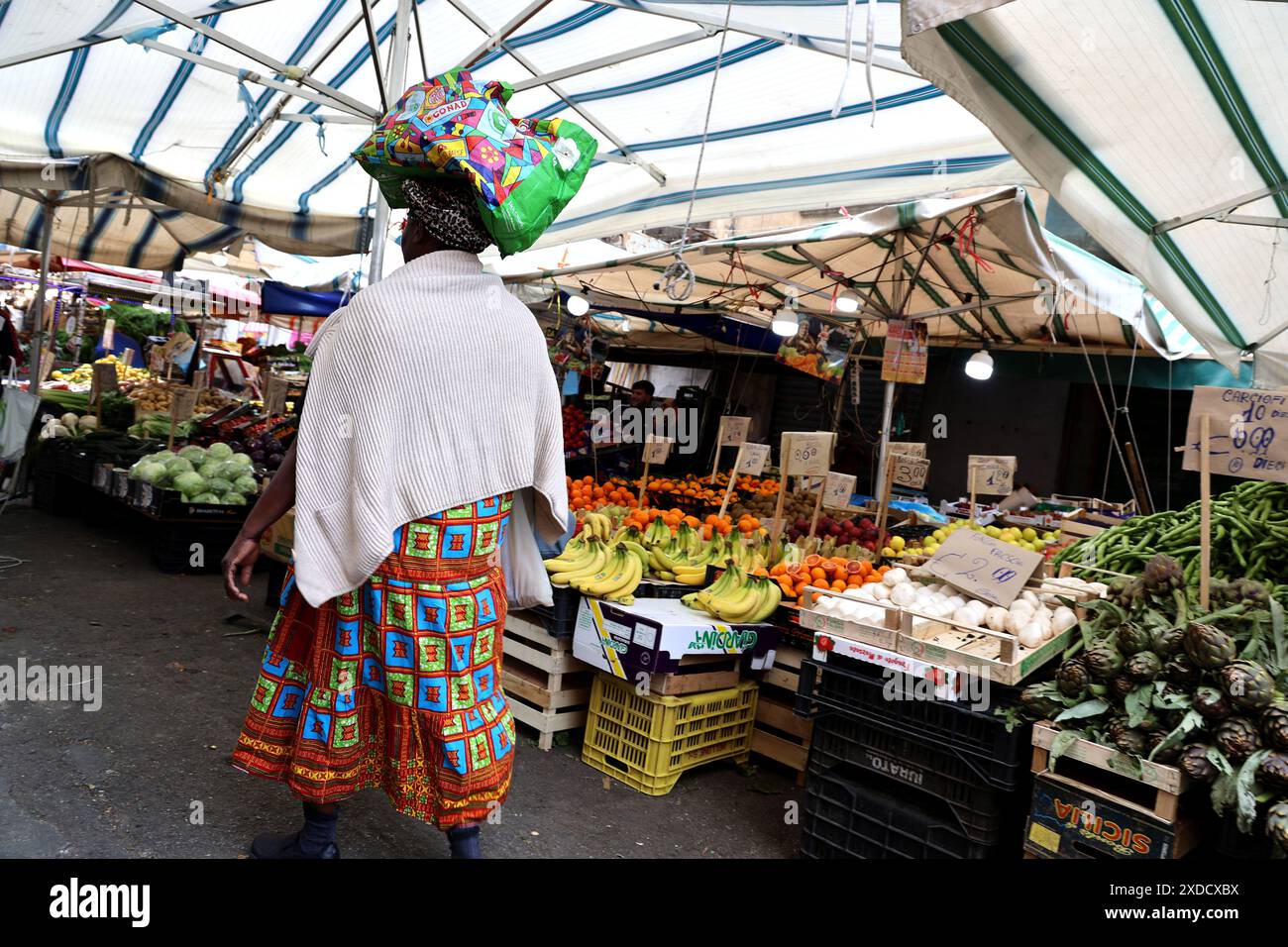 Donna che cammina attraverso il mercato di strada a Palermo, in Sicilia Foto Stock