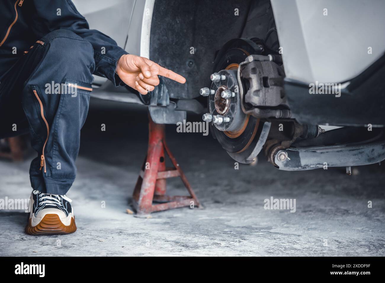 La mano del meccanico di primo piano che punta verso il servizio del sistema di rottura del disco anteriore dell'auto sostituisce la parte rotta. Parte alesaggio centrale. Foto Stock