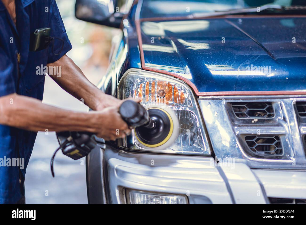 Lucidatura del rivestimento in vetro acrilico dei fari dell'auto, lavoratore nell'officina Auto che utilizza la cera per il rivestimento della lucidatrice nella cura dell'auto. Foto Stock