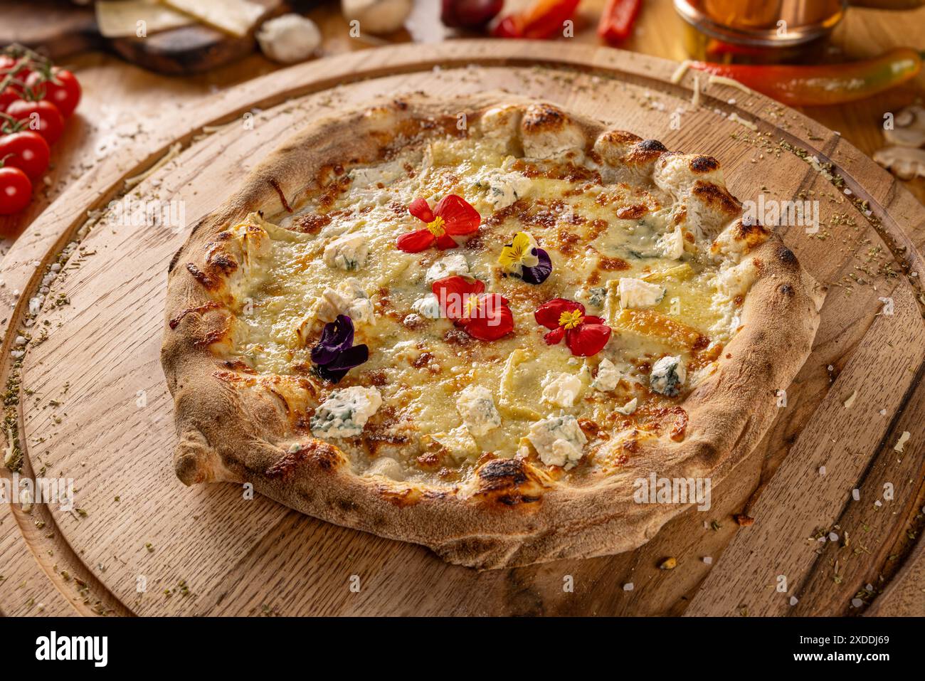 Pizza quattro formaggi decorata con fiori commestibili su tagliere in legno Foto Stock