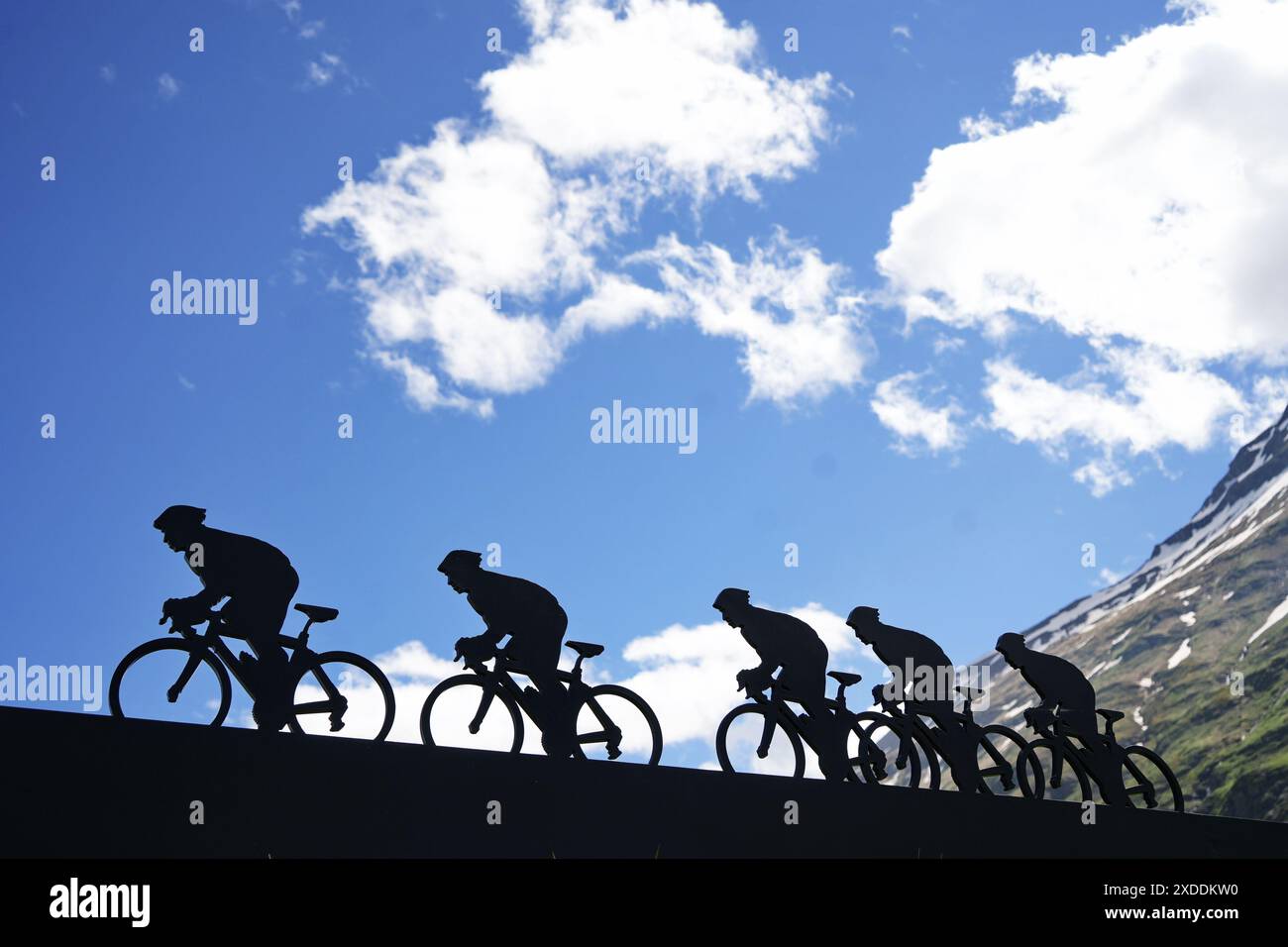 Lanslebourg-Mont-Cenis , Francia - 20 giugno 2024: Un gruppo di ciclisti affronta la ripida salita alpina sotto la luce posteriore. Foto Stock
