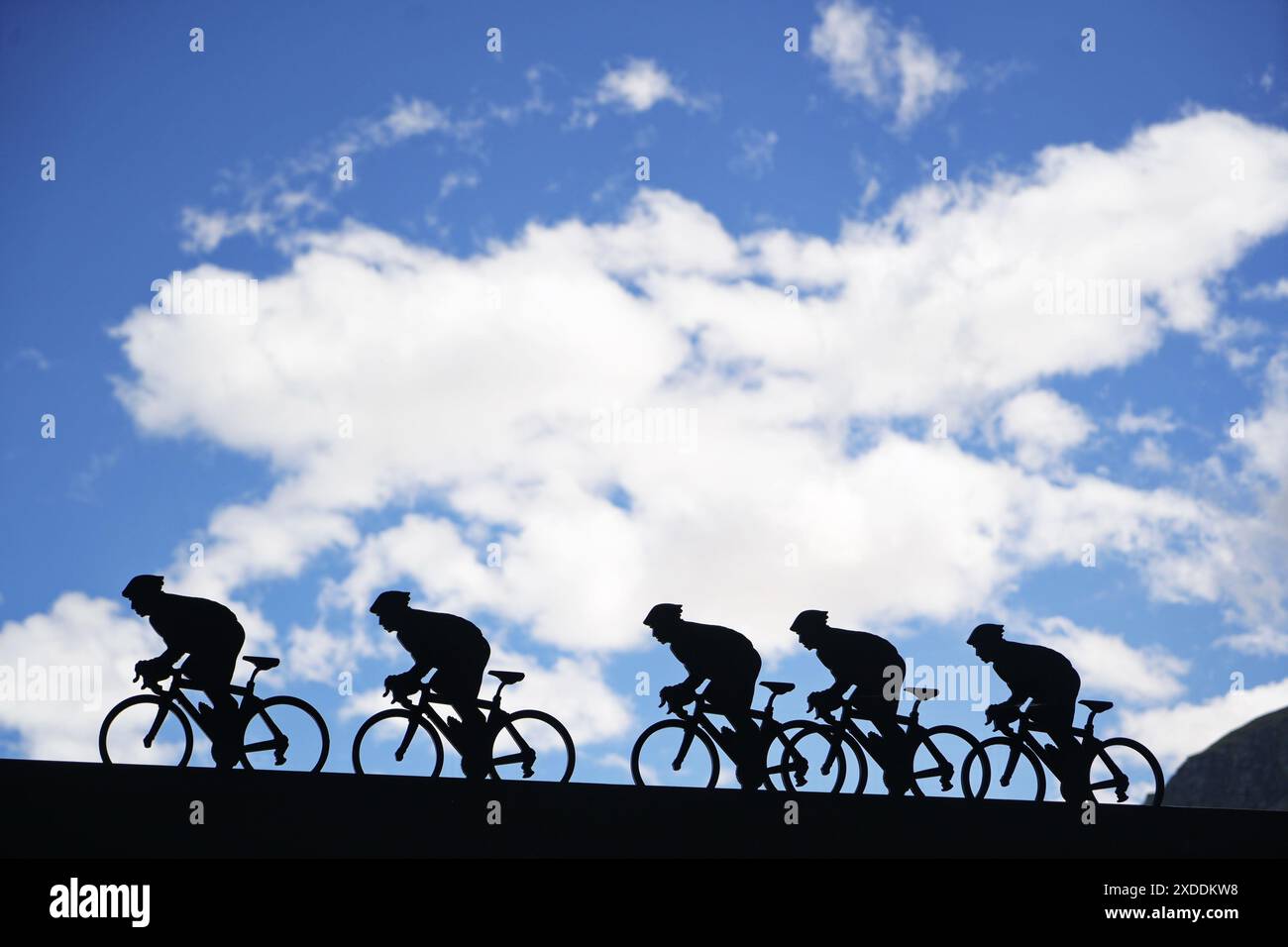 Lanslebourg-Mont-Cenis , Francia - 20 giugno 2024: Un gruppo di ciclisti affronta la ripida salita alpina sotto la luce posteriore. Foto Stock