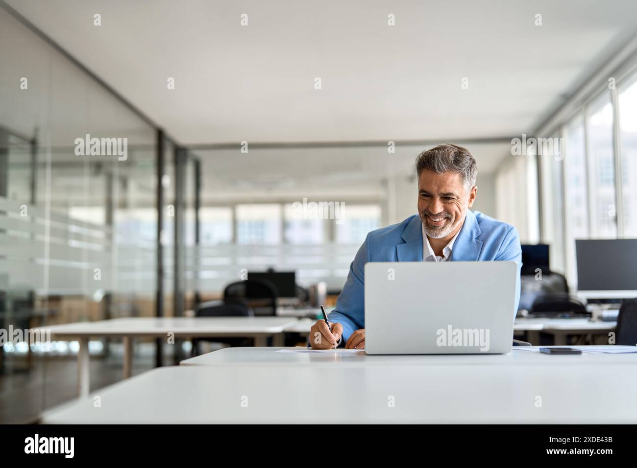 Un uomo d'affari di mezza età che lavora con un notebook in ufficio per scrivere appunti. Foto Stock