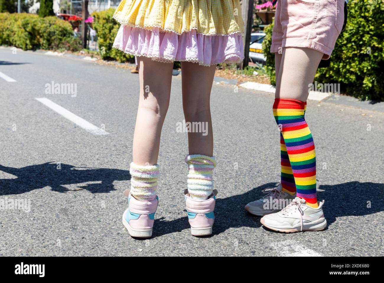 Le gambe delle ragazze in calze al ginocchio. Uno ha calze da ginocchio e sneaker colorate arcobaleno. L'altro ha calzini lunghi rosa anime. Foto Stock