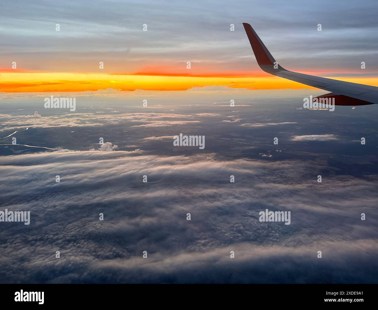 Spettacolare vista del tramonto dalla finestra dell'aereo durante il volo sopra le nuvole Foto Stock