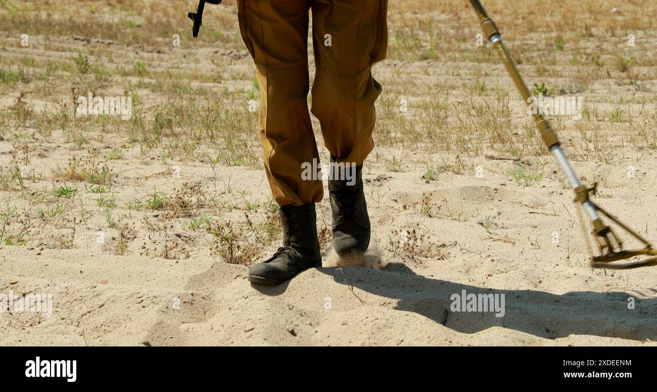 L'ingegnere di combattimento Sapper dell'esercito sovietico, deminatore con un rilevatore di mine in mano, sta cercando mine sul campo. Bomb tech Bomb Squad in Historical Re Foto Stock