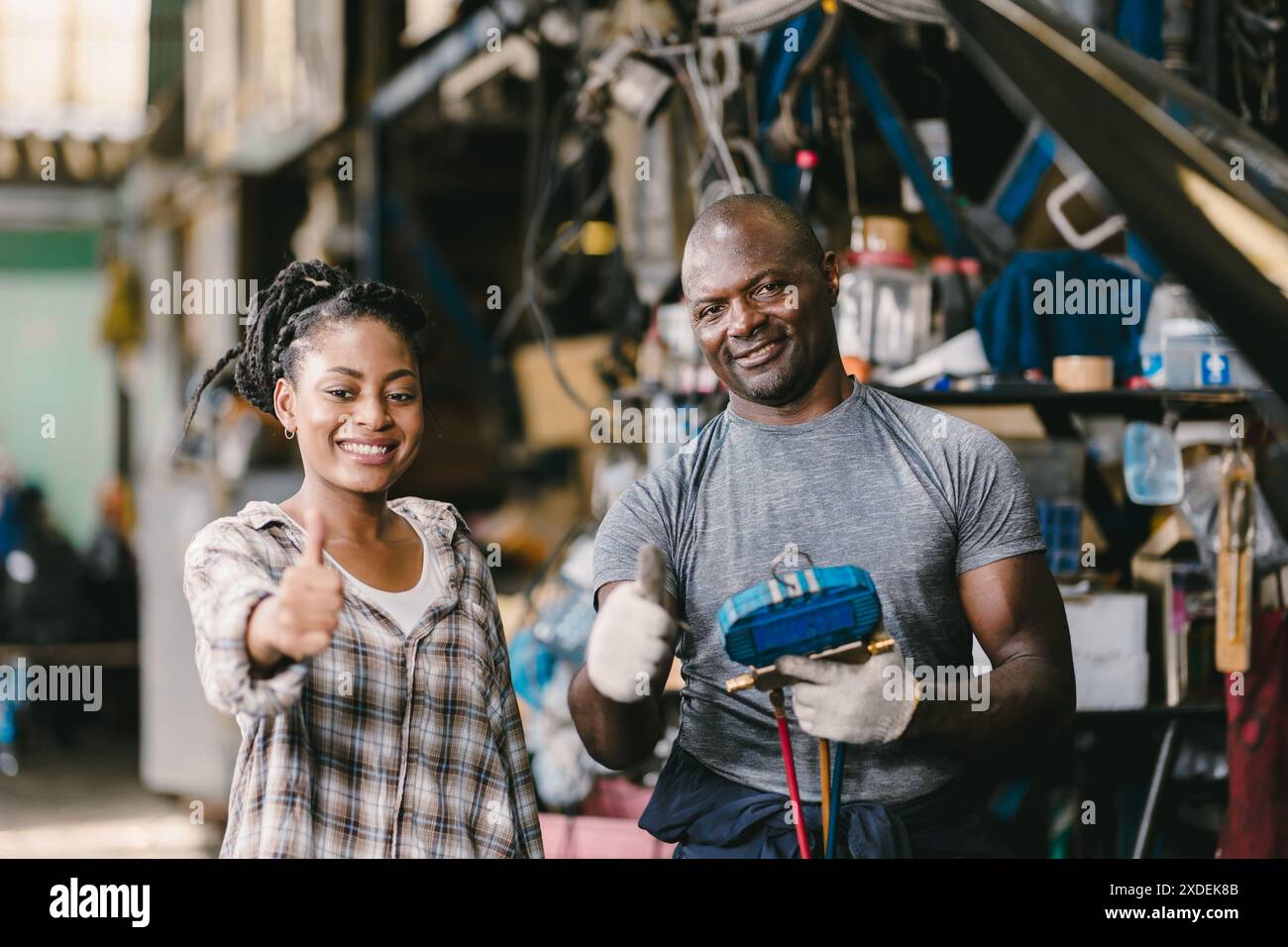Cliente soddisfatto in piedi pollice con un meccanico che risolve il problema dell'auto. Servizio di garage soddisfatto. Foto Stock