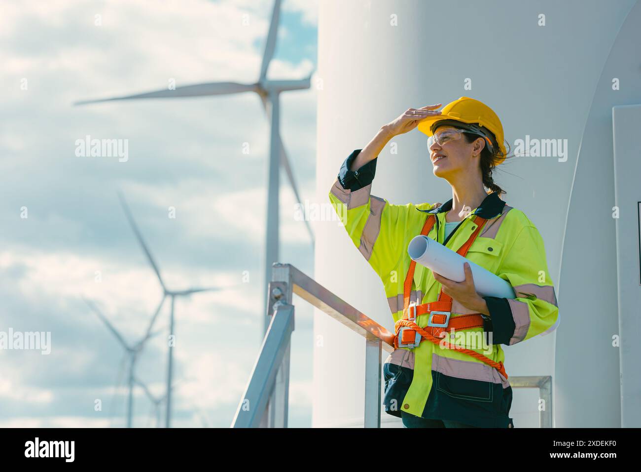 ingegnere donna che lavora all'aperto con sicurezza nelle turbine eoliche background di centrali elettriche a energia pulita, lavoratori con tecnologia per le energie rinnovabili Foto Stock