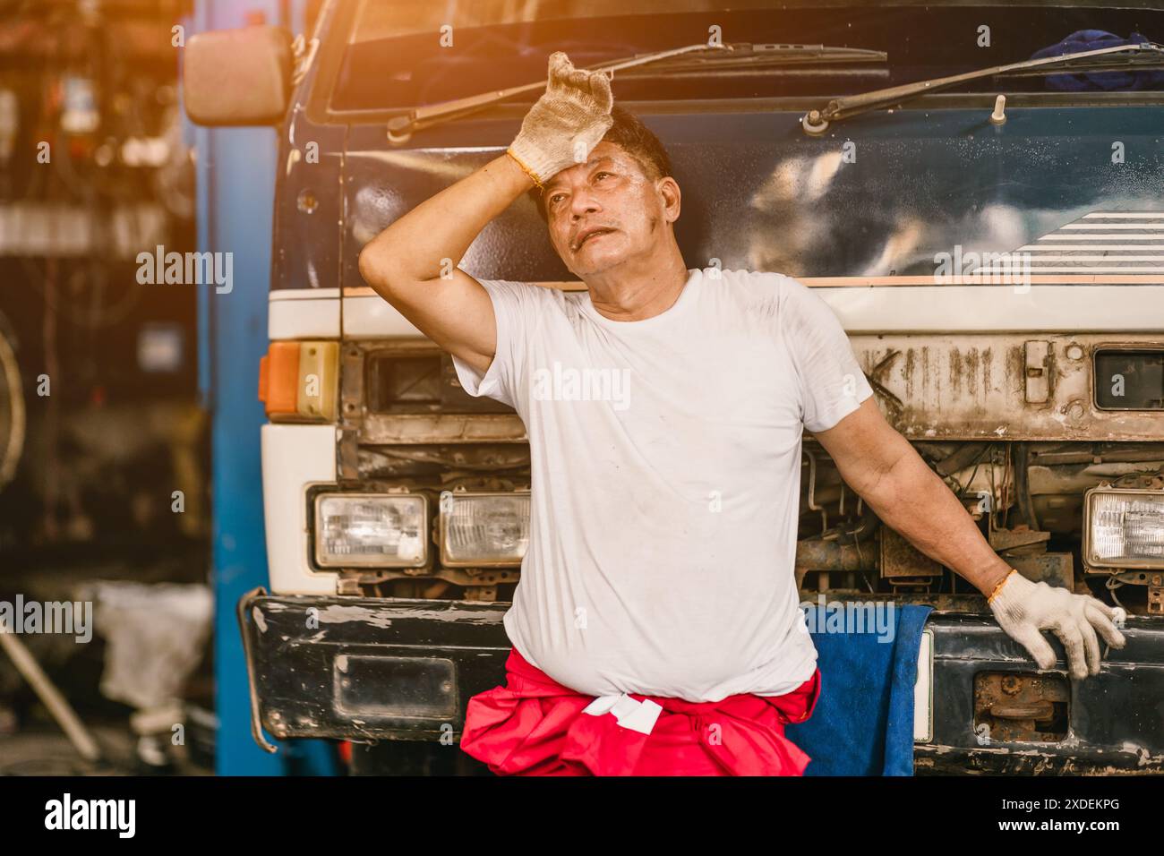 Stanco mal di testa esausto problema di salute lavorando duro lavoro nel servizio auto del garage. Foto Stock