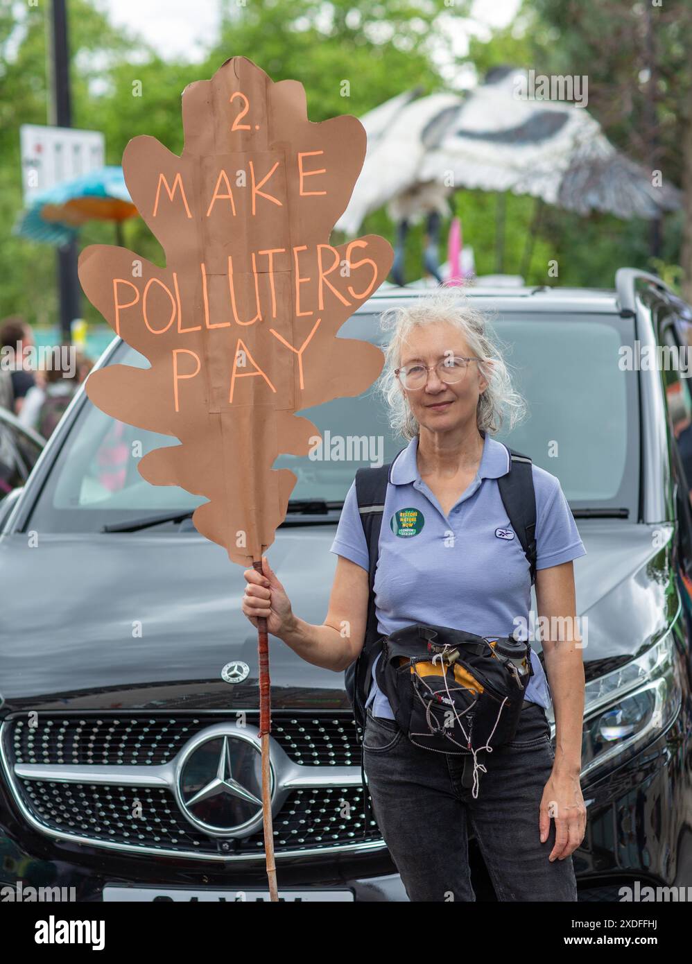 Vista posteriore di una giovane donna con un cartello che ripristina la natura selvaggia a Londra, Regno Unito Foto Stock