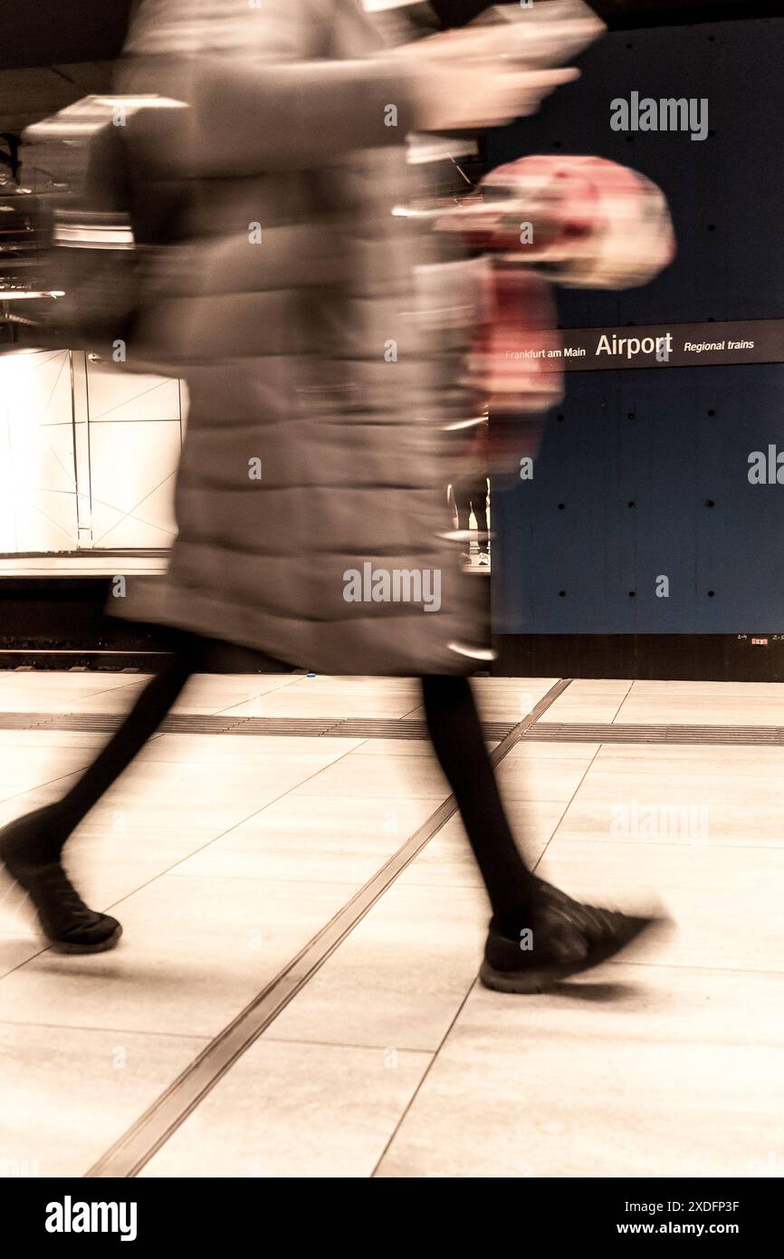Una persona cammina rapidamente su una piattaforma della metropolitana verso un cartello dell'aeroporto, la sua forma è offuscata dal movimento. Foto Stock