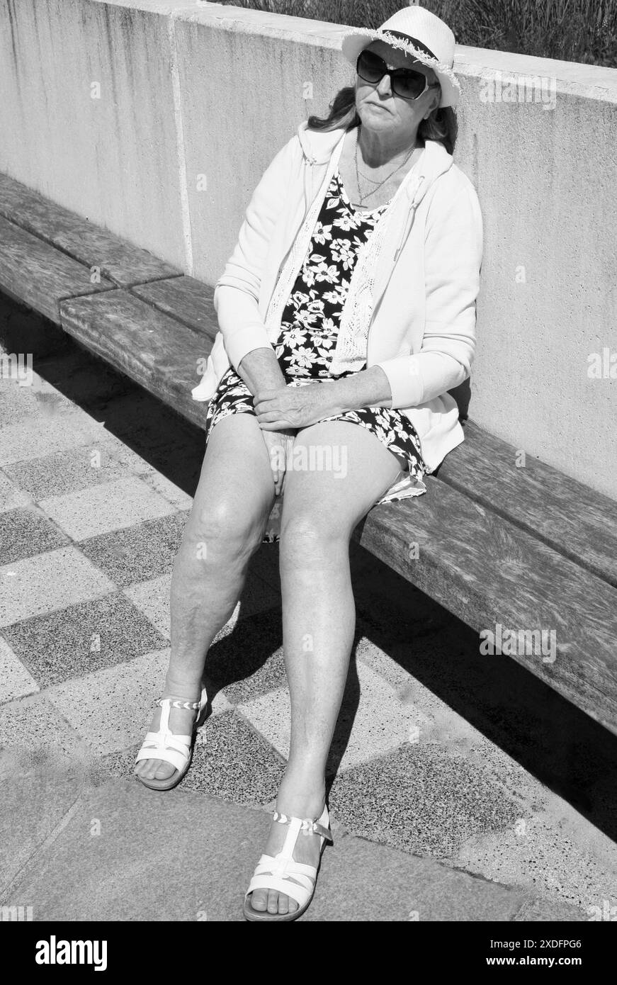 Una donna anziana che si rilassa sul lungomare, in una calda giornata di sole. Foto Stock