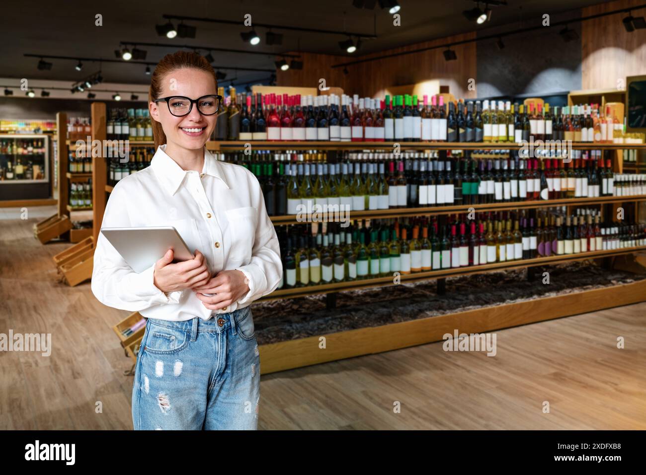 Ritratto di una donna dipendente o proprietaria di un negozio di alcolici. Donna d'affari con un tablet digitale sta in un'enoteca e sorride. Foto Stock
