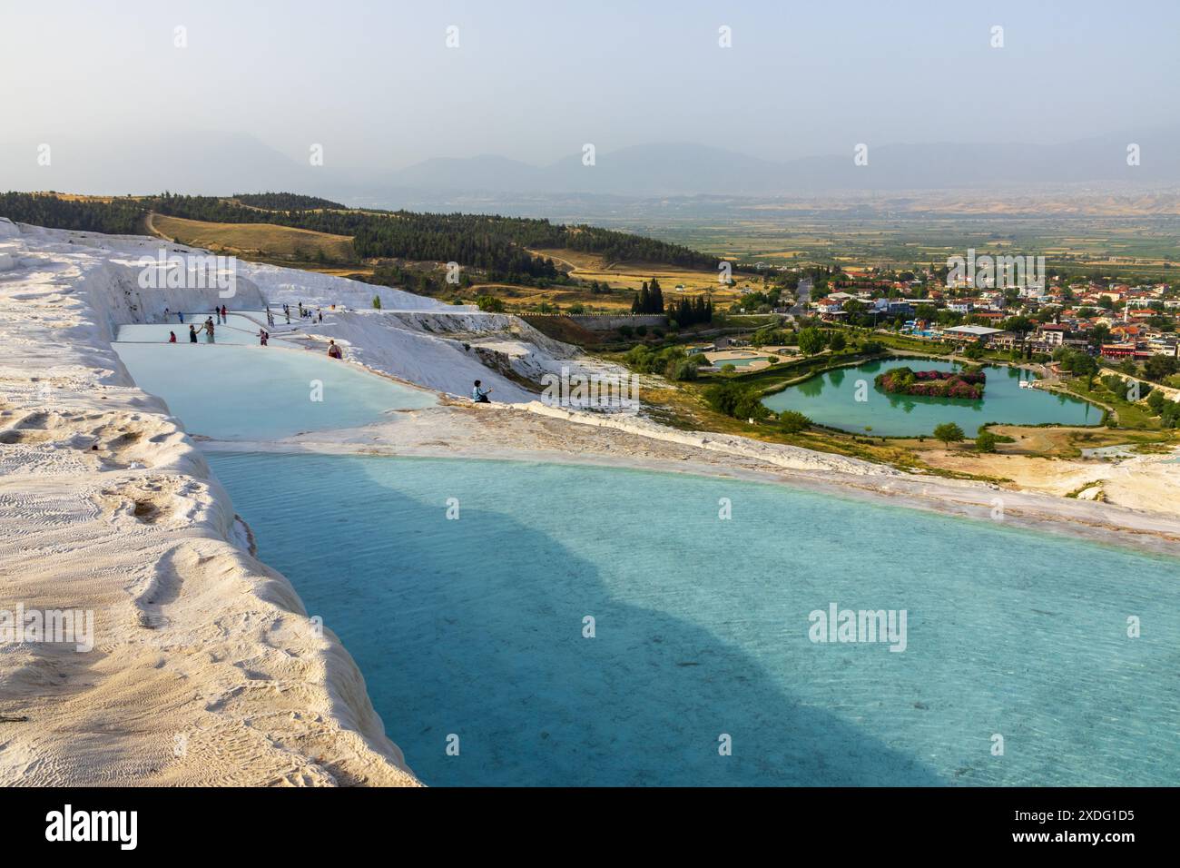 Persone che camminano sulle bellissime travertini bianche di Pamukkale a Türkiye in una giornata di sole, godendosi le classiche vedute dalle piscine sulla collina. Foto Stock