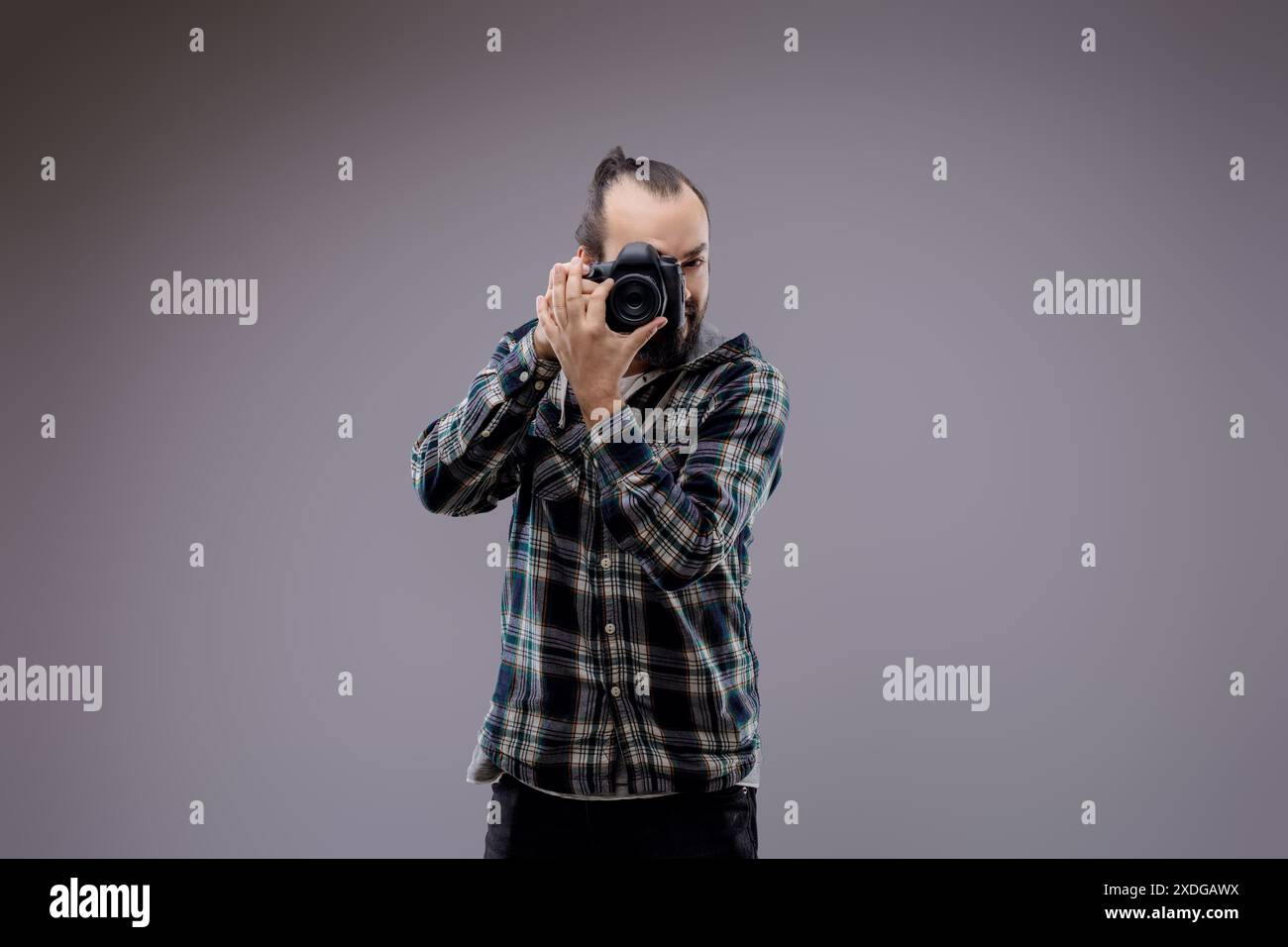 Fotografo sicuro che inquadra lo scatto con una fotocamera professionale in studio. Un appassionato hobbista mette in mostra creatività e abilità Foto Stock