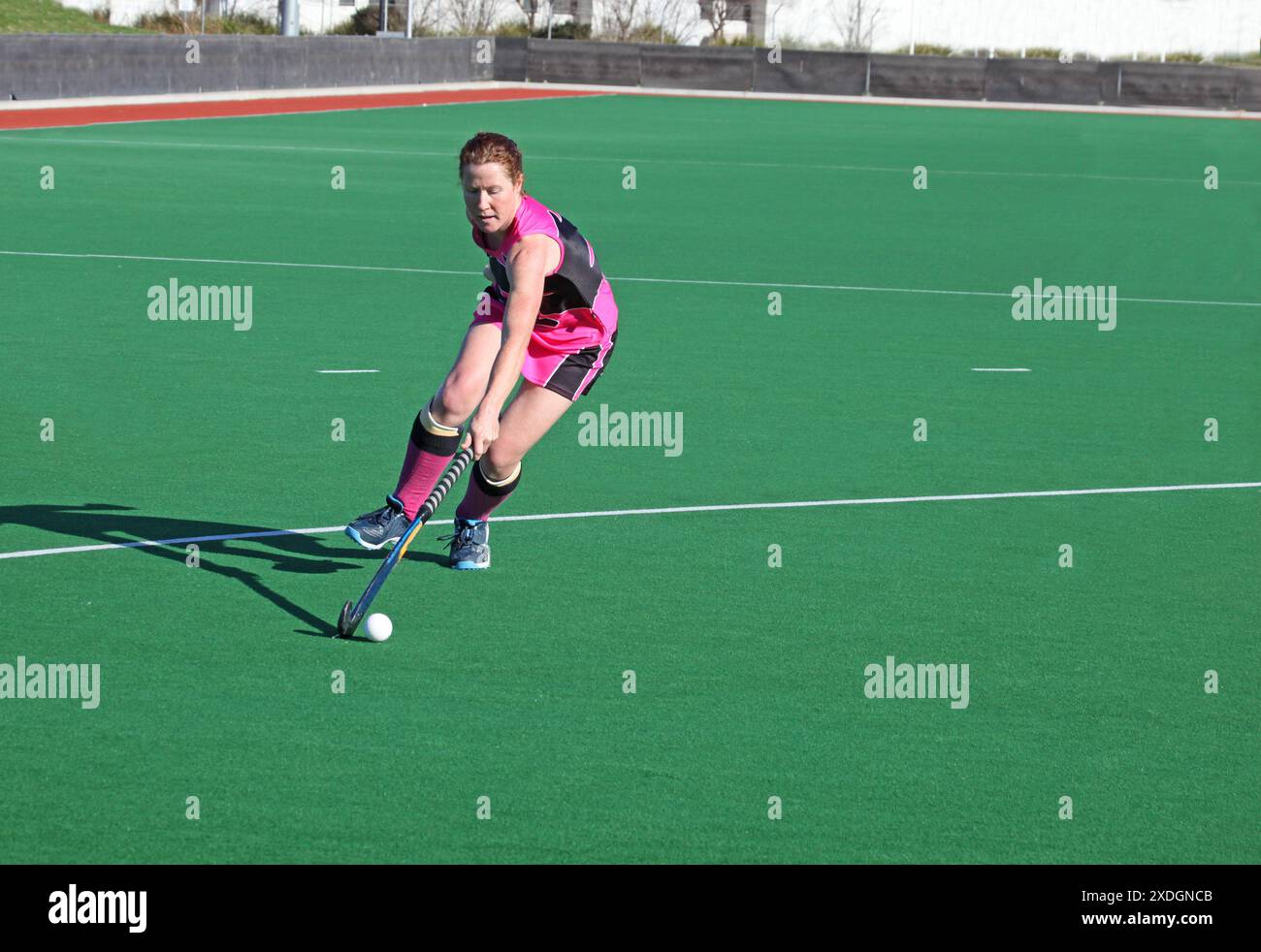 Una donna che si allunga completamente porta la palla nel cerchio in una partita di hockey su prato. Foto Stock