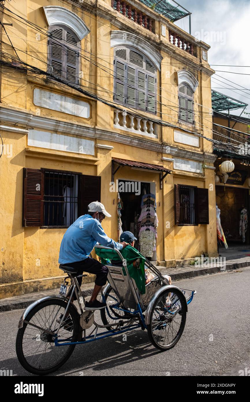 Vietnam taxi servizio triciclo turisti in bicicletta in giro per la città. Operaio vietnamita in sella a triciclo per i viaggiatori in servizio. Cyclo è mos Foto Stock