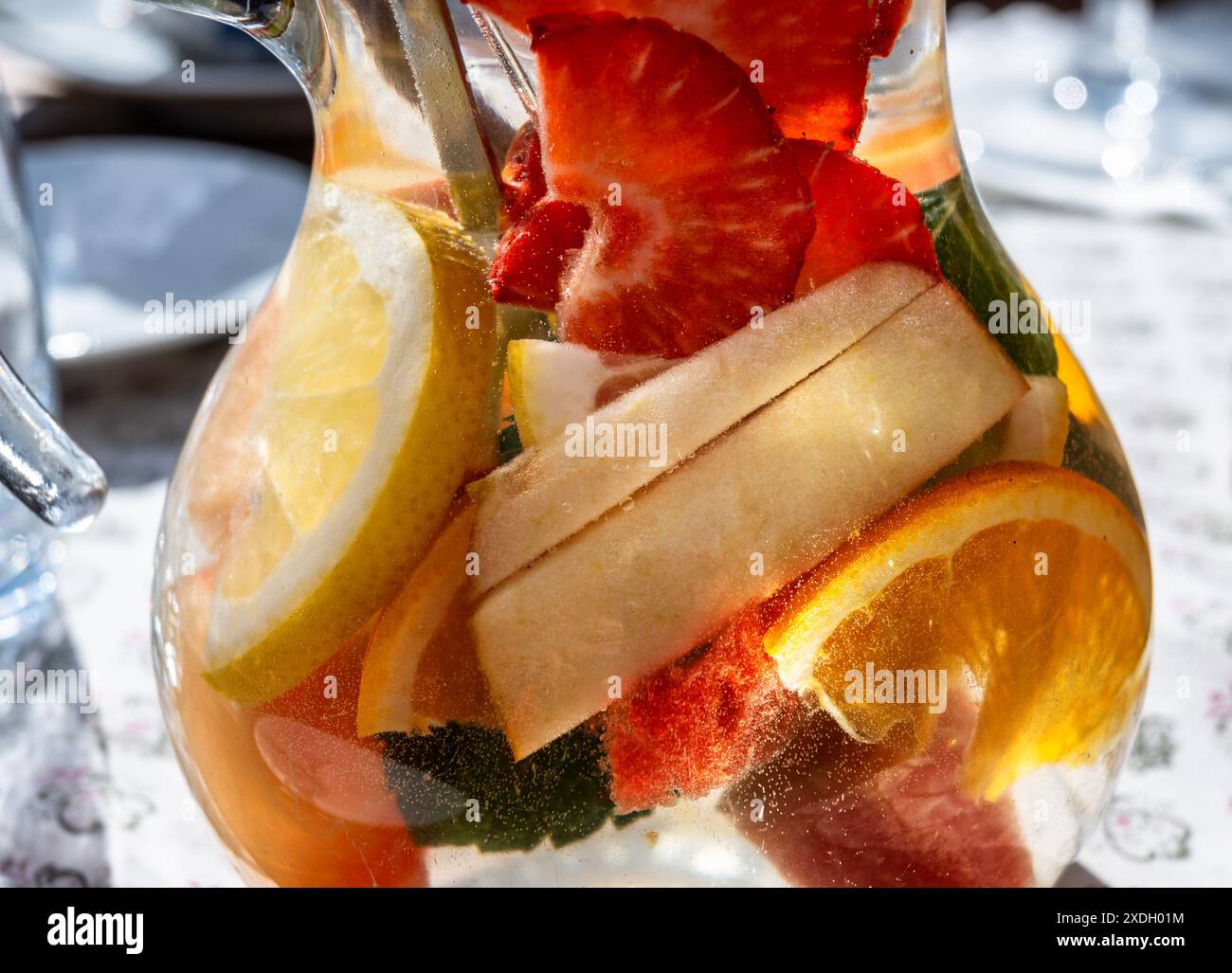 Molti affettavano la frutta in acqua in una caraffa di vetro. Rinfrescante bevanda vitaminica nella stagione estiva. Primo piano. Foto Stock