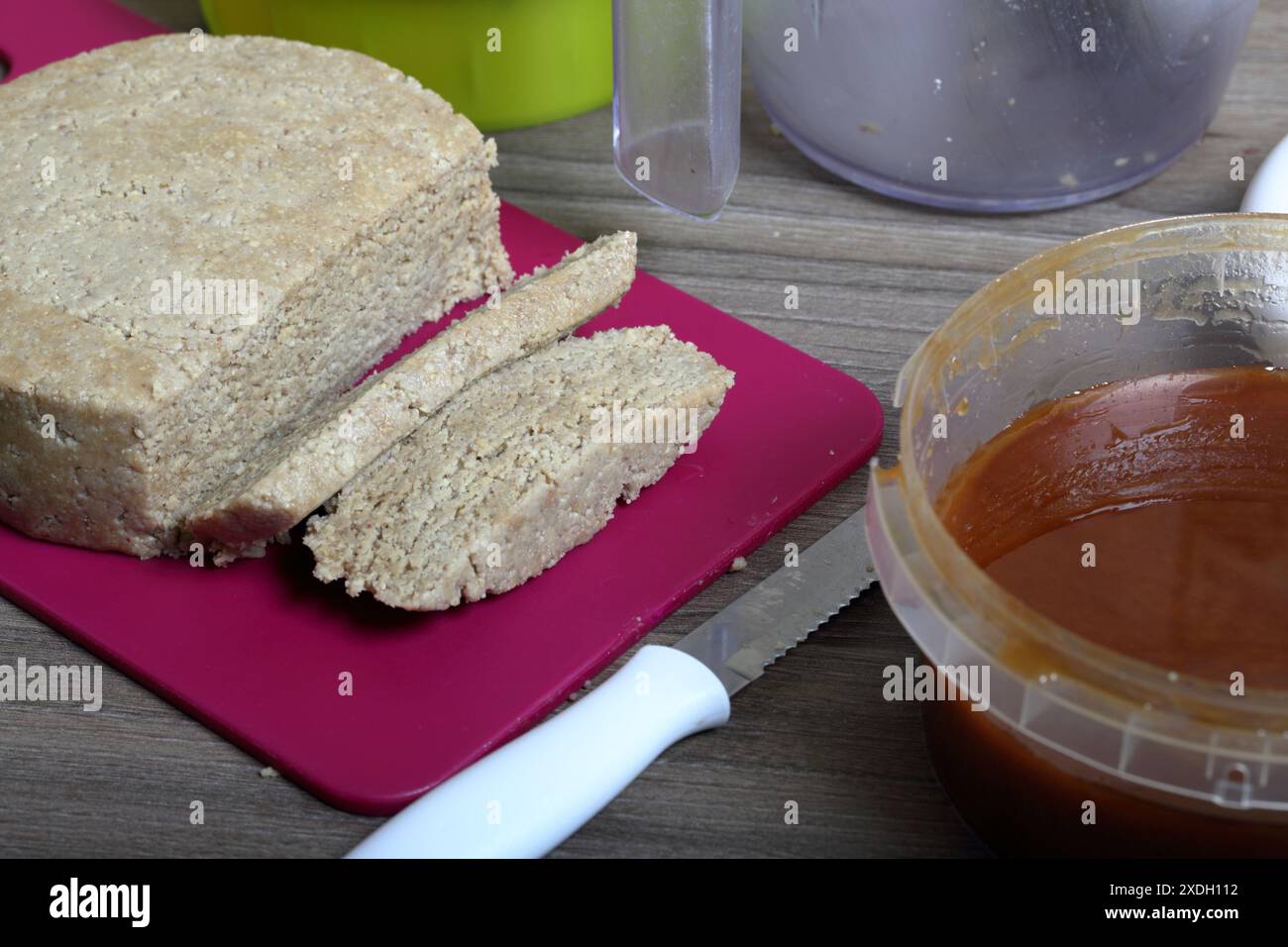 Alva tagliata a fette di miele, arachidi e semi di girasole. Il prossimo miele nel contenitore. Ingredienti e strumenti per la preparazione dell'halva. Foto Stock