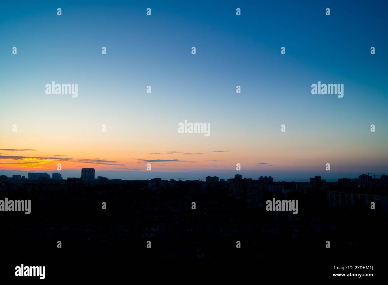 Cinque minuti prima dell'alba sulla città. Cielo quasi limpido con un'area luminosa sopra l'orizzonte. Sagome di edifici in controluce Foto Stock