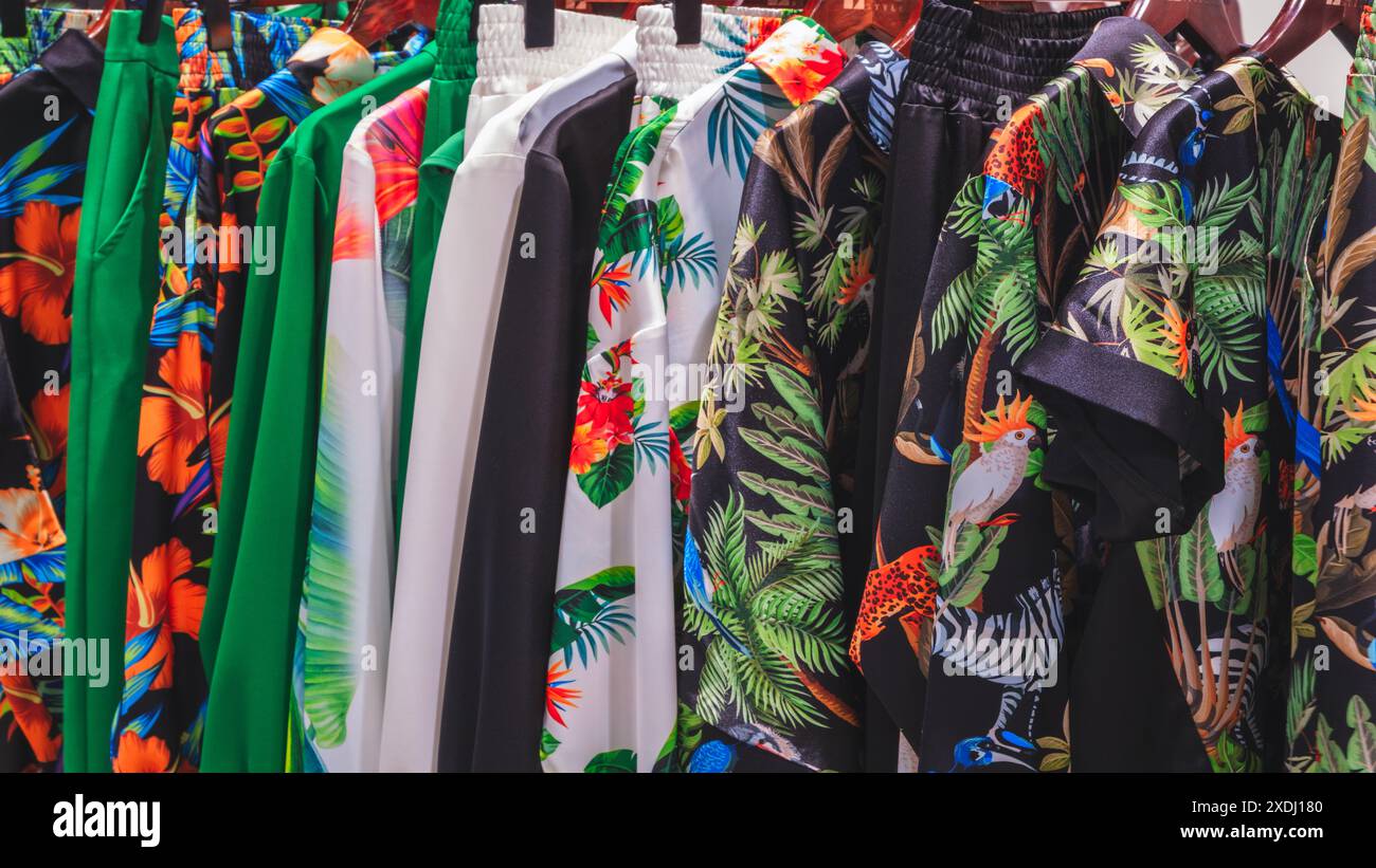 Una fila di camicie colorate con stampe tropicali appese su un rack. Le camicie sono disposte in modo che siano tutte visibili e facili da vedere. La scena lo è Foto Stock