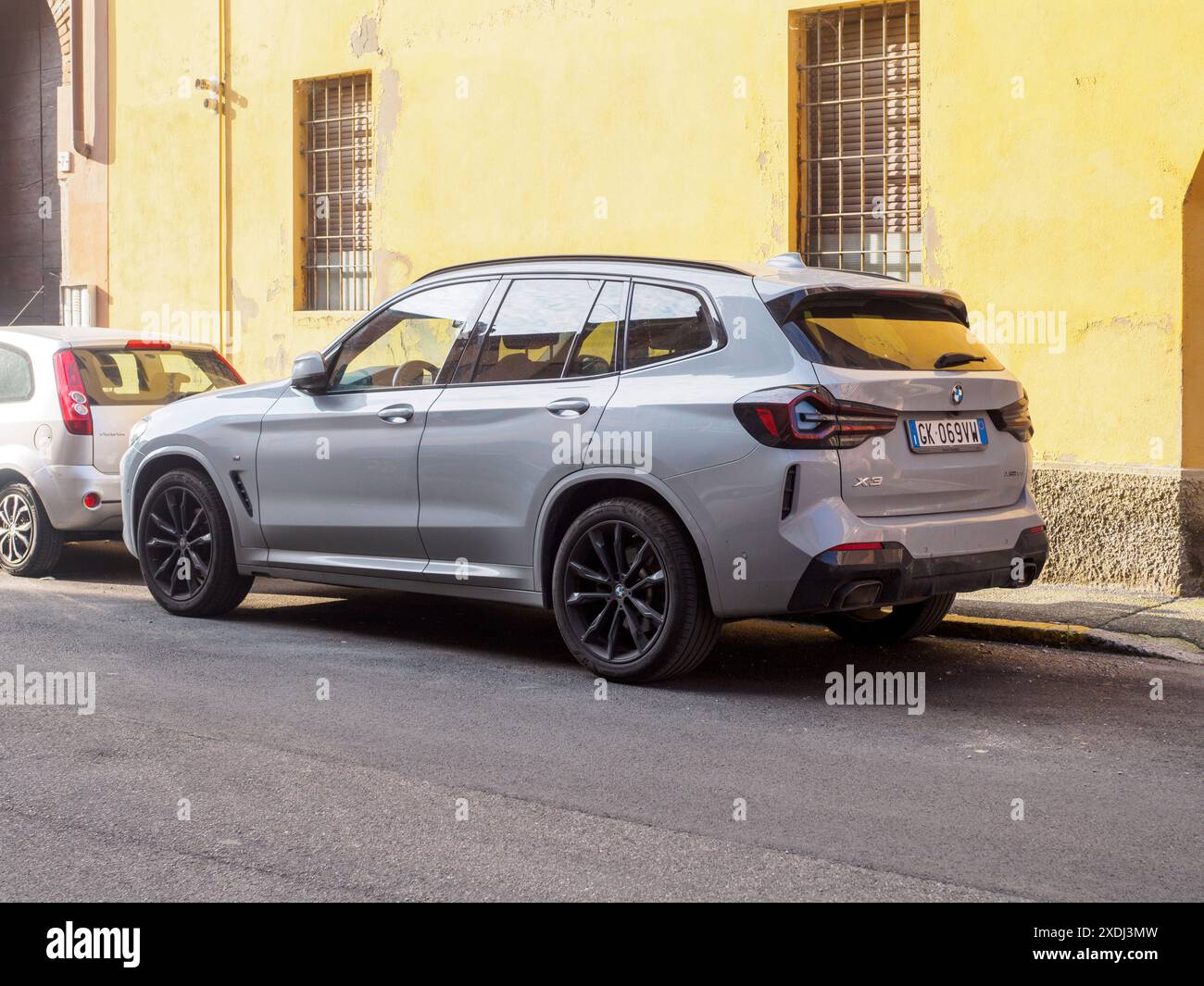Cremona, Italia - 21 giugno 2024 moderno suv metallizzato bmw x3 grigio è parcheggiato sul lato di una strada asfaltata, di fronte a un edificio giallo con vittoria bloccata Foto Stock