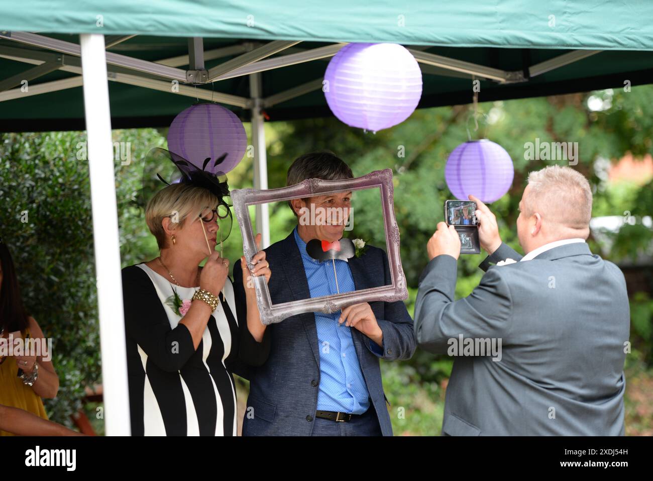 Gli ospiti del matrimonio fotografano gli altri ospiti nella cabina fotografica al matrimonio con il telefono cellulare Foto Stock