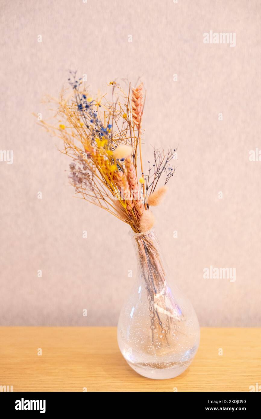 bouquet di fiori secchi ed erbe aromatiche in vaso di vetro sullo sfondo della parete. Natura morta in stile rustico. Luce dura. Cartolina con spazio per il testo. Foto Stock