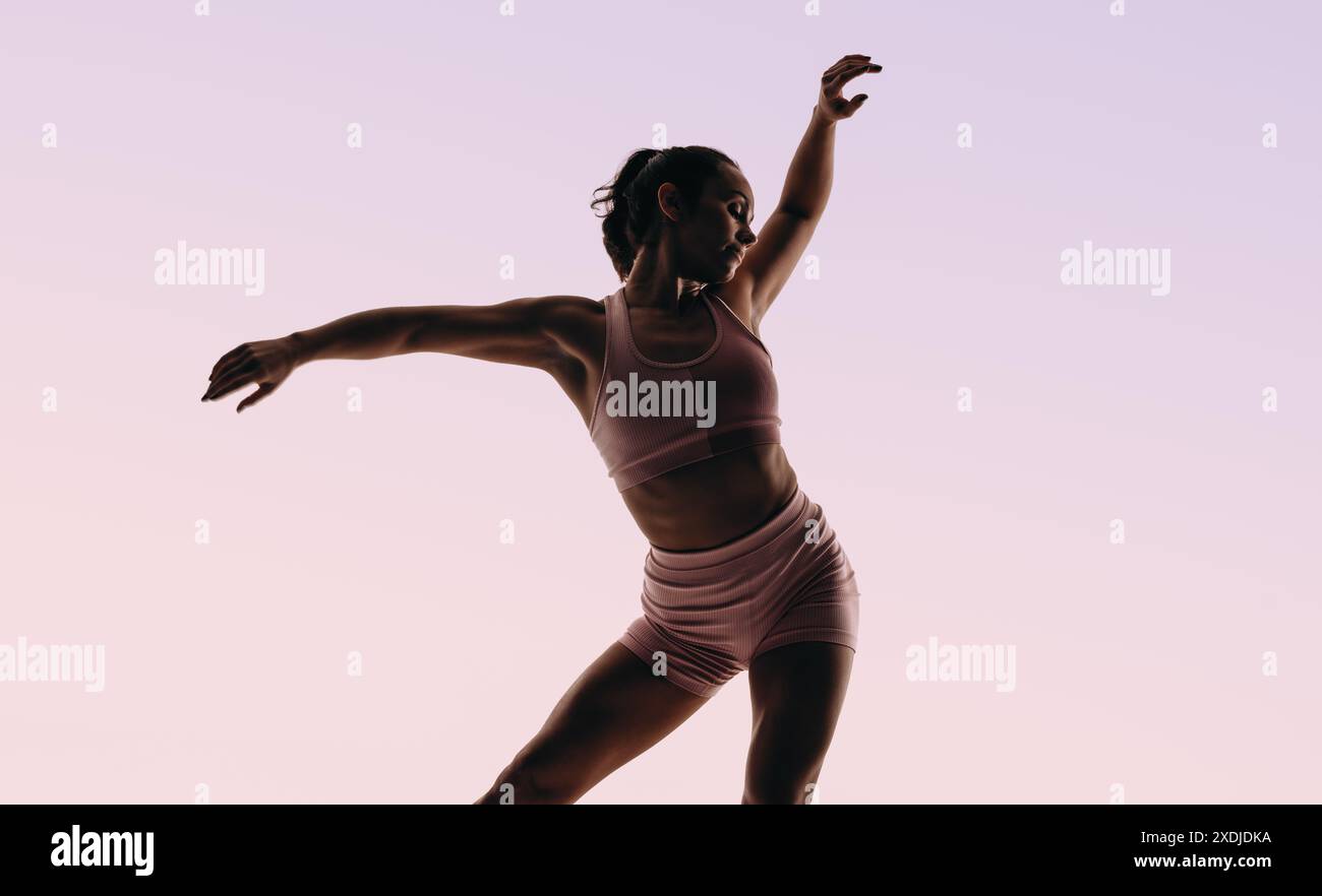 Ballerino di balletto esegue una routine artistica con forma impeccabile e flessibilità. La sua forma fisica e i suoi movimenti sapienti incarnano l'eleganza e la grazia Foto Stock