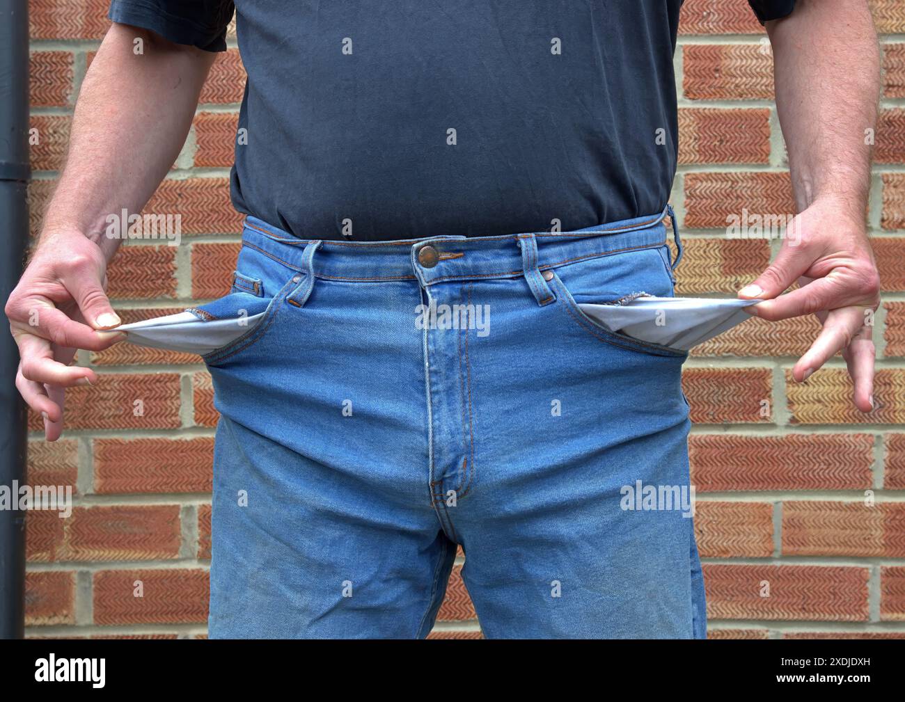 Persona che tiene fuori tasche vuote senza soldi Foto Stock