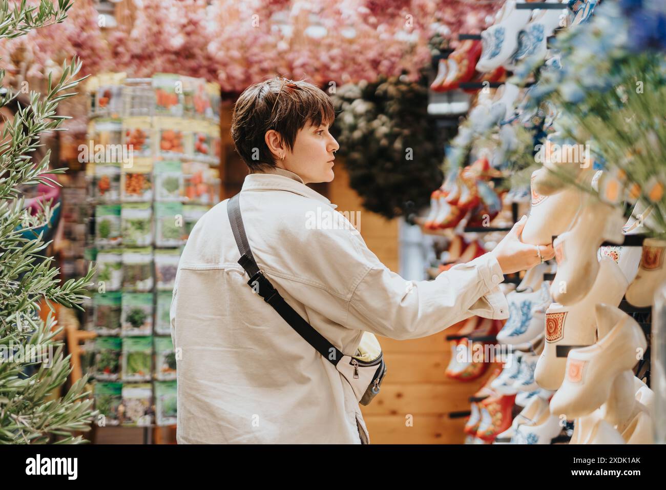 Persona che fa shopping in un negozio con varie scarpe in ceramica in esposizione e una vivace vegetazione sullo sfondo Foto Stock