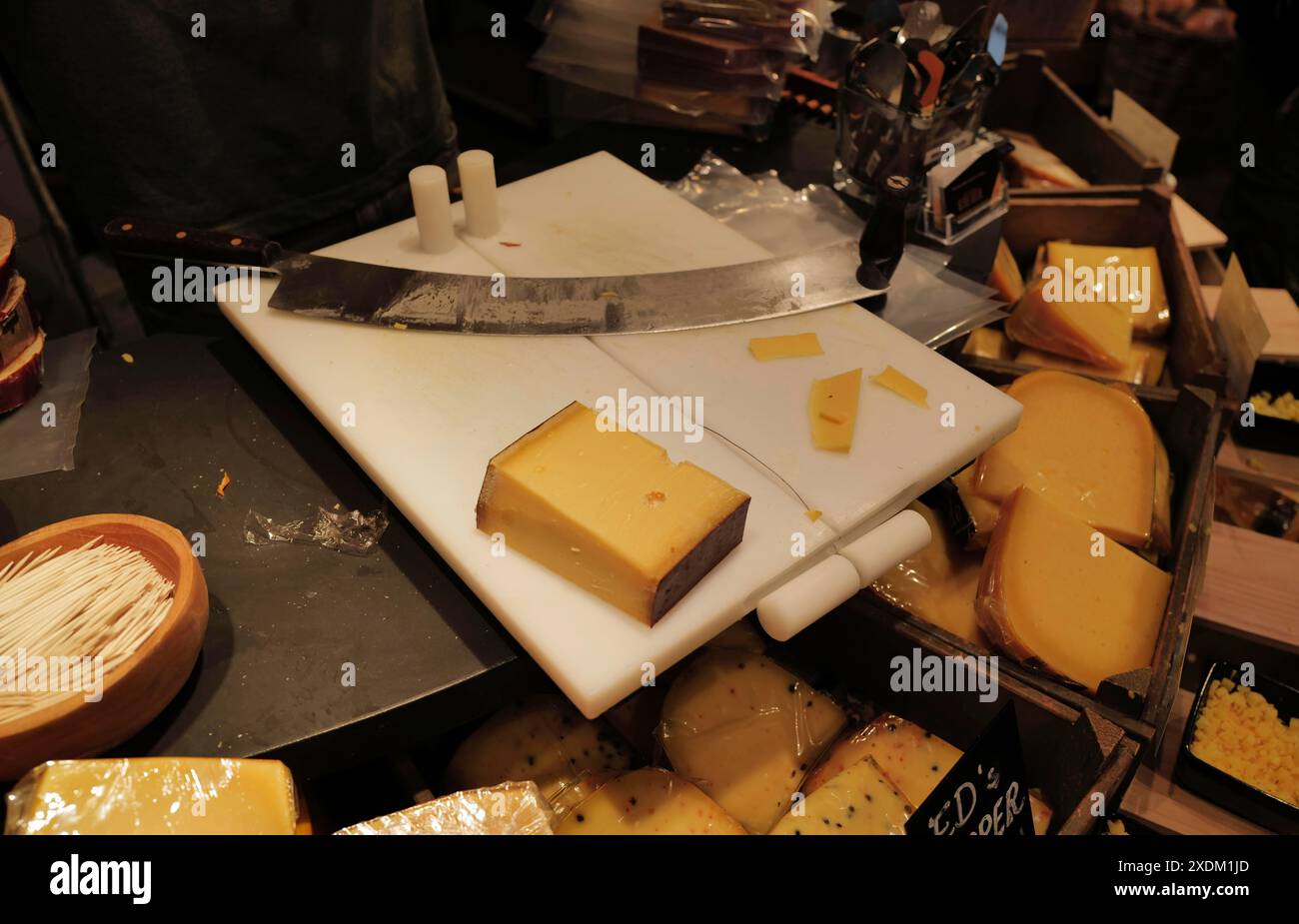 Un affettatore di formaggio e blocchi di formaggio su un tagliere in un negozio di formaggi. Amsterdam, Paesi Bassi Foto Stock