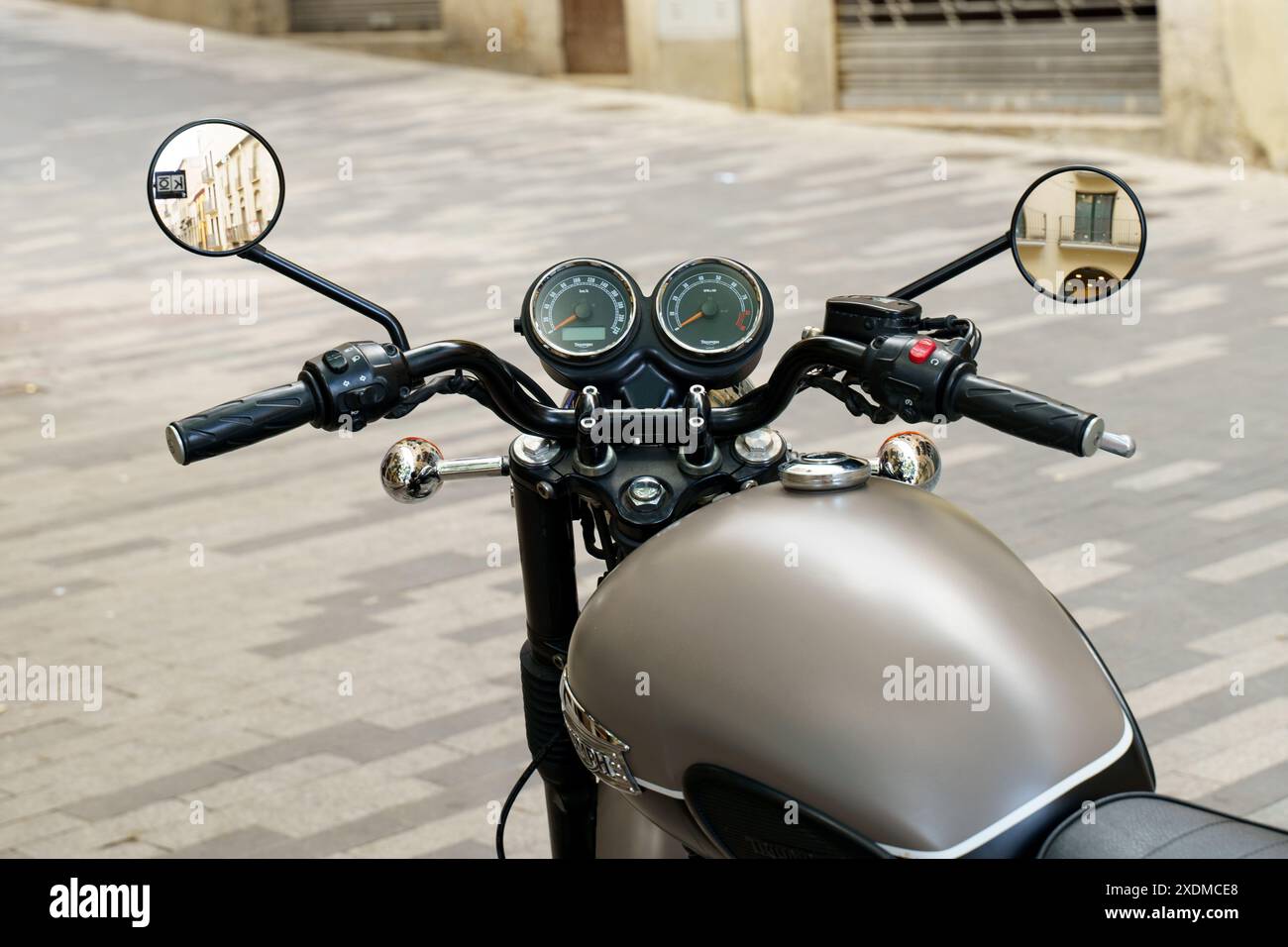 Figueres, Spagna - 14 maggio 2023: Una motocicletta è parcheggiata sul lato di una trafficata strada urbana, circondata da edifici e pedoni di passaggio. Foto Stock